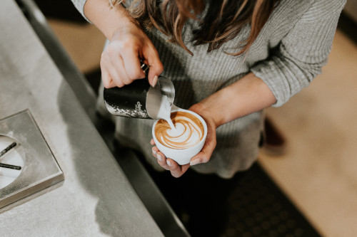 Woman pouring cappuccino coffee