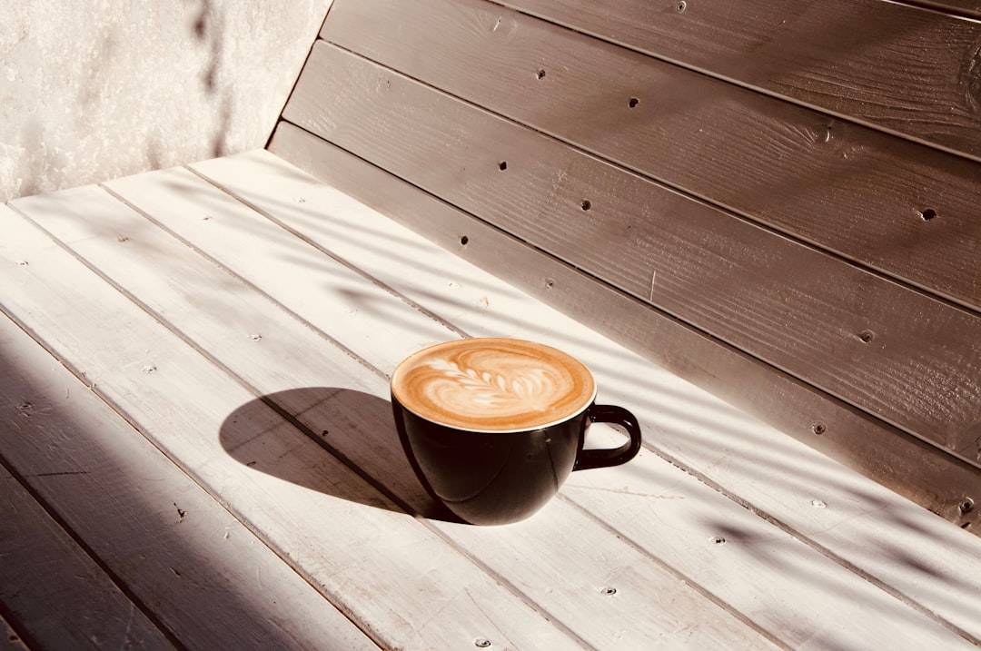 A mug of pumpkin spice latte on a bench in autumn
